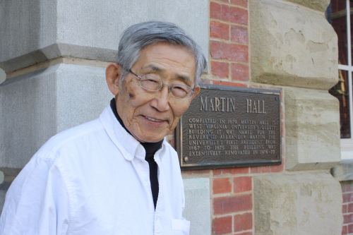 Image of Kyong Wong LEe standing in front of a placard that says "Martin Hall"