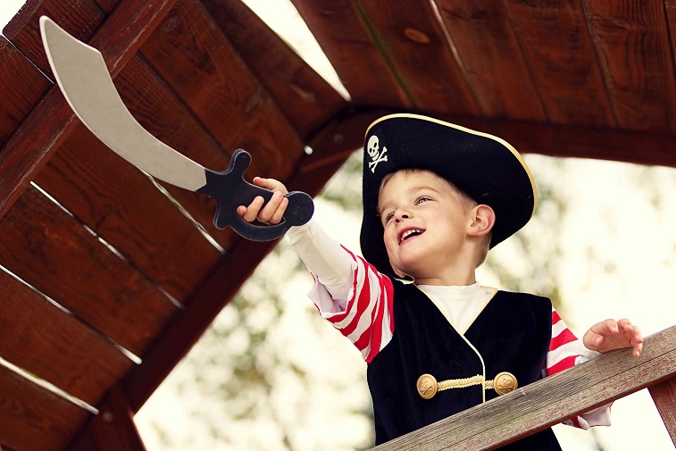 A young boy in a pirate costume holding out a scimitar