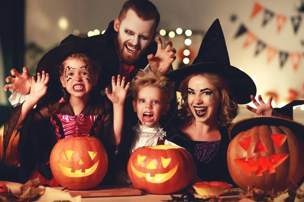 Picture of a family wearing Halloween customes in front of pumpkins.