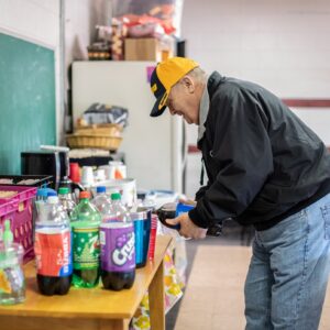 Senior man pours soda at a Lunch and Learn event.