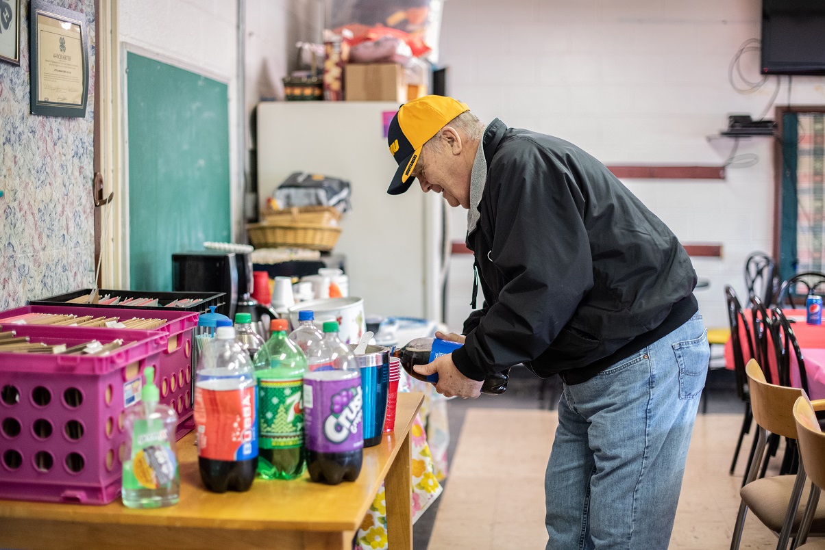 Senior man pours soda at a Lunch and Learn event.
