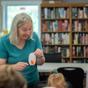 Librarian showing children how to make a craft.
